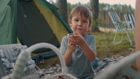 preschooler-boy-is-playing-with-folding-knife-at-family-picnic-at-nature-tent-camp-in-forest-for-family